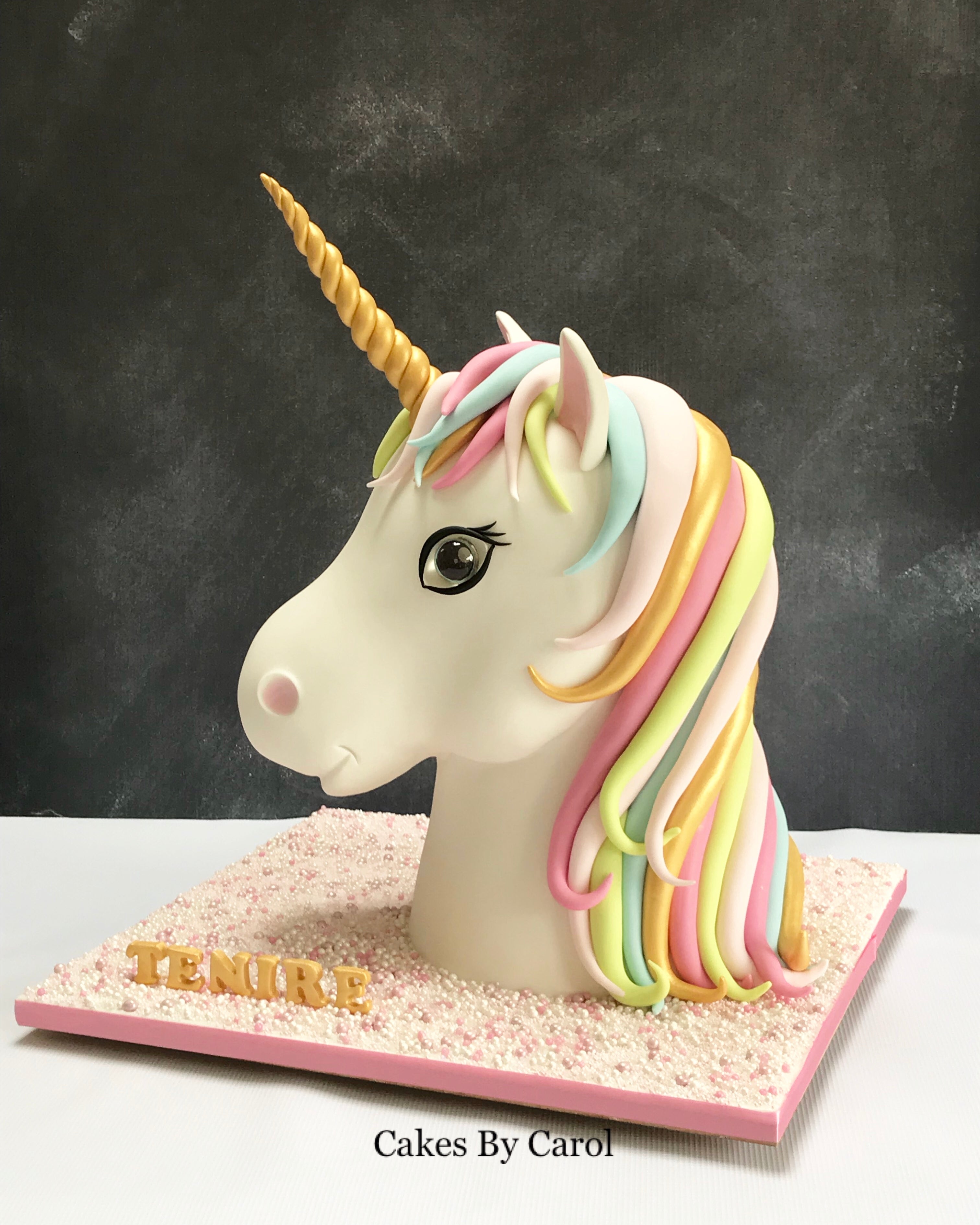 Unicorn cake with colorful mane on a stand against a dark background